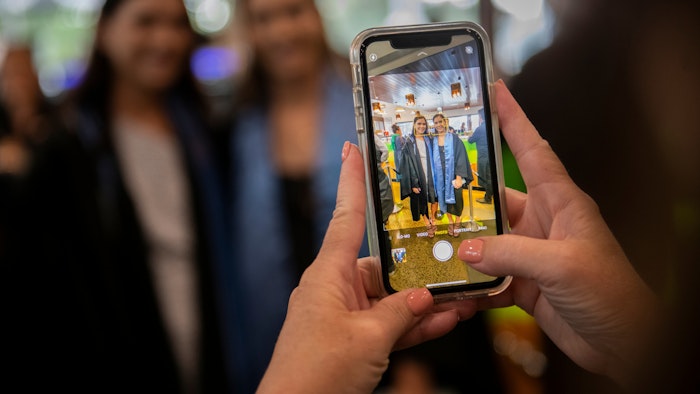 Friend taking photo of graduates with iPhone