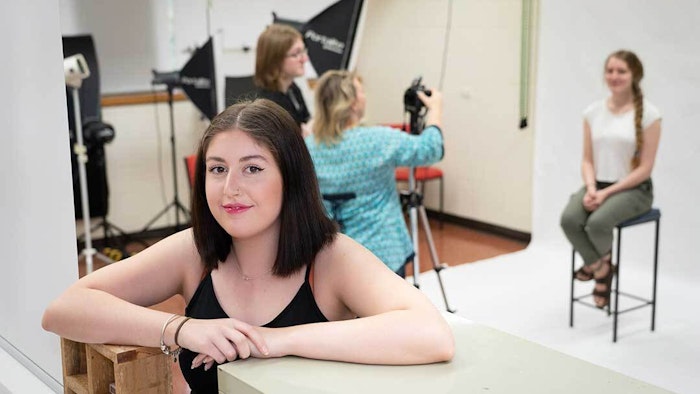 GOTAFE Graphic Design student squatting down with a photoshoot going on in the background