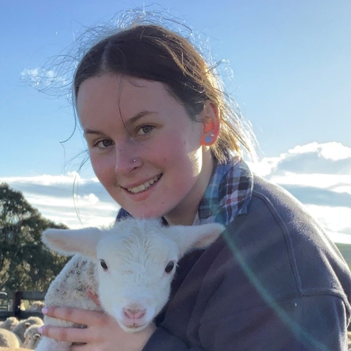 Erin Mumford School Based Apprentice holding lamb on farm