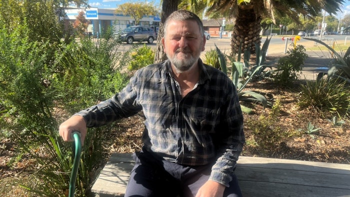 Man sits on bench in garden.