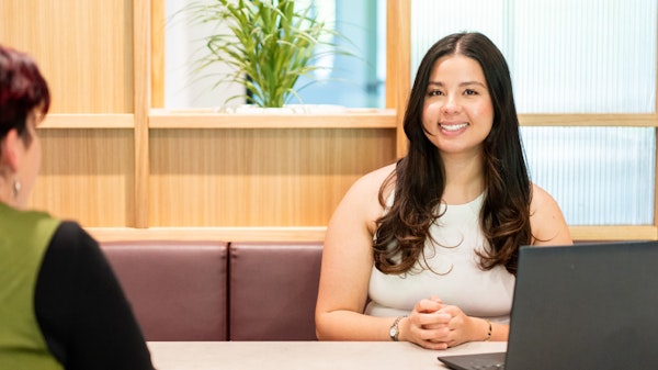 Employee talking to someone with a laptop on a table