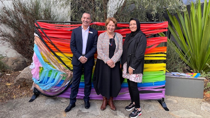 Three GOTAFE staff members in front of pride flag