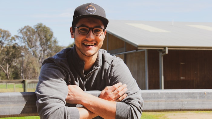 Julian leaning on a fence smiling in the sun