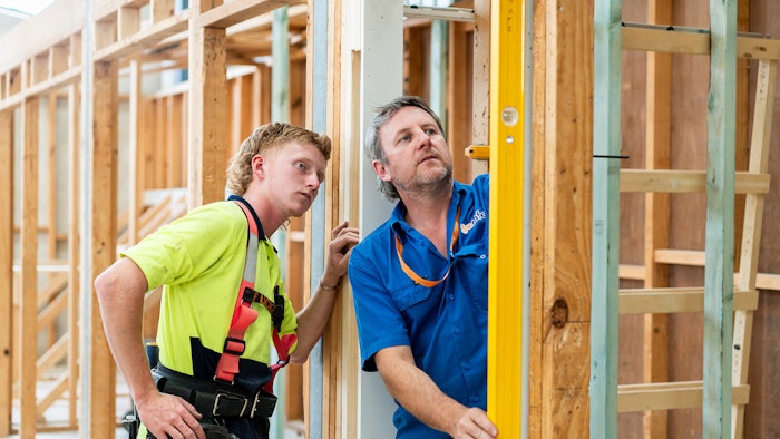 two tradesmen wearing hi-vis and safety equipment