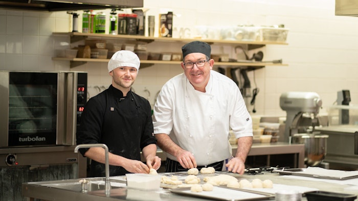 GOTAFE Baking Student holding a baked cake standing side on