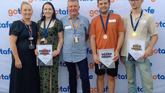trainers and students holding their worldskills certificates standing infront of GOTAFE wall